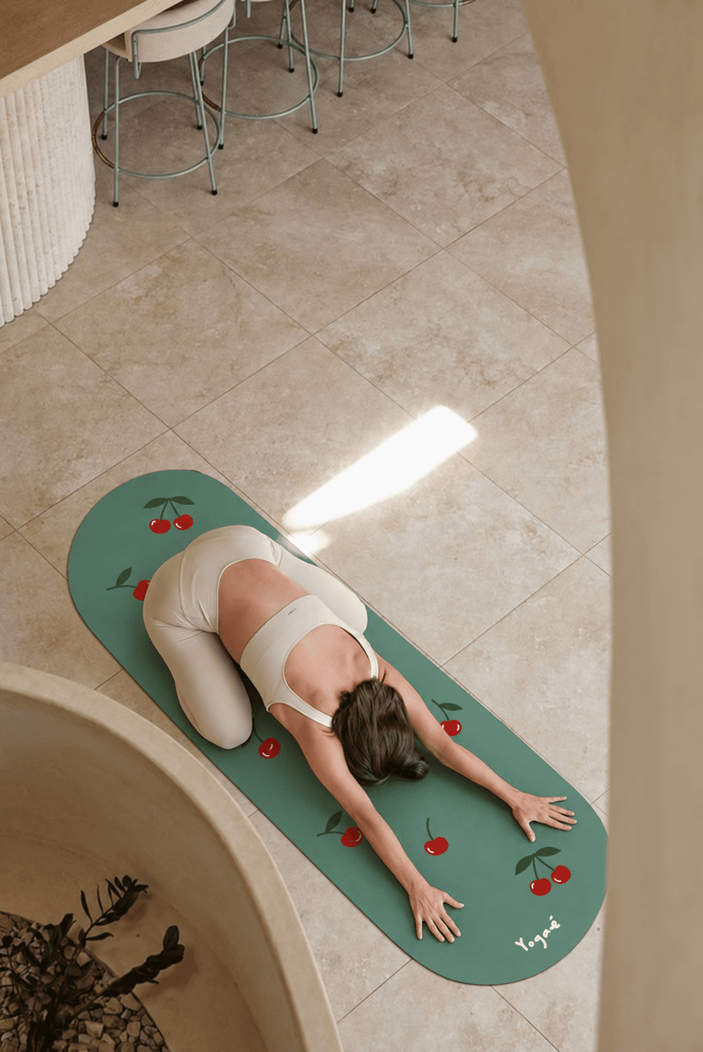 Vue du dessus, posture repliée sur tapis Yogaé sauge à motif cerises, intérieur minéral