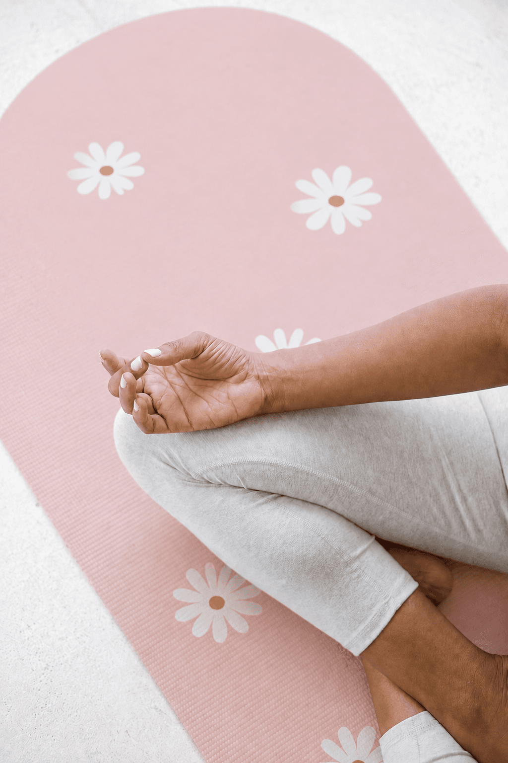 Main posée sur tapis Yogaé blush à motif marguerites, gros plan