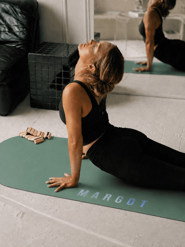 Margot en posture sur tapis Yogaé vert sauge personnalisé, miroir et lumière claire